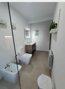 a white bathroom with a toilet and a sink at El Resbalón in Comillas +18 photos