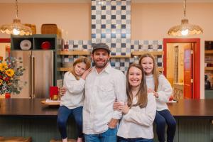 a man and two girls are standing in a kitchen at Luxe 1920 Schoolhouse Sleeps 8 30 Min From Okc in Guthrie