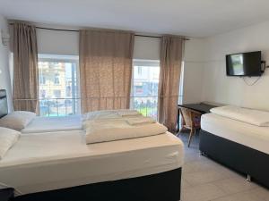 a bedroom with two beds and a desk and a balcony at Hotel Garni Emir in Cologne