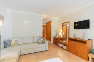 a living room with a couch and a flat screen tv at Quinta Velha Oasis, Pool Resort in Cabanas de Tavira