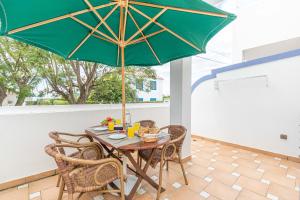 a table with a green umbrella on a patio at Quinta Velha Oasis, Pool Resort in Cabanas de Tavira