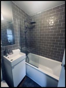a bathroom with a white sink and a bath tub at Coastal Cwtch in Moffat