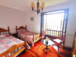a bedroom with two beds and a table and a window at El Resbalón in Comillas