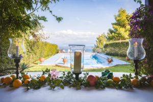 a table with two wine glasses and oranges on it with a pool at Villa Blue Lagoon in Afitos +11 photos