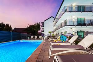 a swimming pool with lounge chairs next to a building at KASHUBIAN Resort in Władysławowo