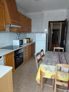 eine Küche mit einem Tisch mit Stühlen und einem Kühlschrank in der Unterkunft Vila Morena in Grândola
