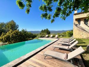 a pool with lounge chairs next to a building at provence living in Roussillon
