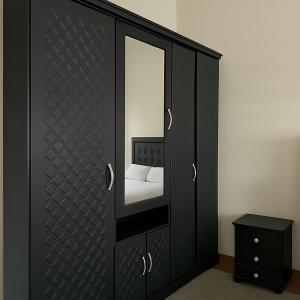 a black cabinet with a mirror and a bed at Résidence Kawtar Meknès in Meknès