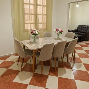 a dining room table with chairs and vases with flowers on it at Résidence Kawtar Meknès in Meknès