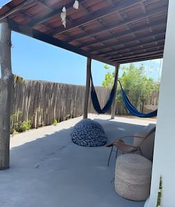 a porch with a hammock and a fence at Casa aconchegante com piscina na praia da Barrinha in Barrinha