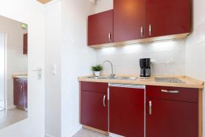 une cuisine avec des armoires rouges et un évier dans l'établissement Strandhafer 1 Utkiekerblick, à Burgtiefe auf Fehmarn 