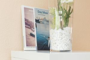 a vase with flowers on a shelf with two magazines at Haus Panorama Laboe Nr 21 in Laboe +24 photos