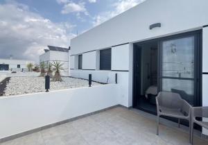 a white house with a balcony with a chair at Villa El Loto Blanco in Dolores