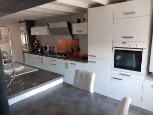 a kitchen with white cabinets and a sink and a microwave at Isabelle's charming roof! in Beaune