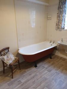 a bath tub in a bathroom with a chair and a sink at Kirkwood - Real Farm Holidays & Experiences in Dalton +55 photos