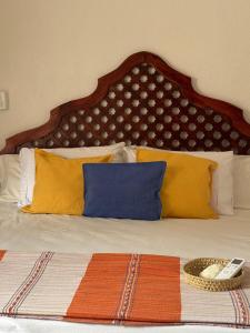 un lit avec des oreillers jaunes et bleus et une télécommande dans l'établissement casa vacacional, à Puerto Escondido 7 autres photos