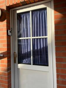 a white door with a window with blue curtains at Ostseemuschel Laboe in Laboe