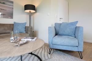 a living room with a blue chair and a table at Kellenhüs in Kellenhusen