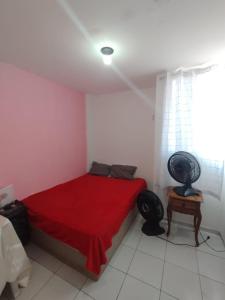 a bedroom with a bed with a red blanket and a table at ALUGUEL TEMPORADA QUARTo DE CASAL NO CATOLÉ PARA SÃO JOÃO in Campina Grande