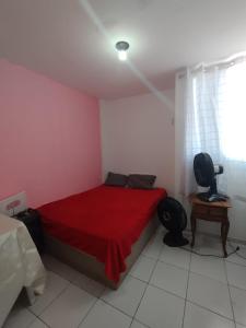a bedroom with a red bed and a desk and a chair at ALUGUEL TEMPORADA QUARTo DE CASAL NO CATOLÉ PARA SÃO JOÃO in Campina Grande