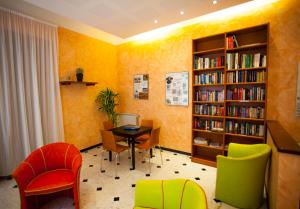 biblioteca con mesa, sillas y estantería de libros en Hotel Delle Rose, en Bonassola
