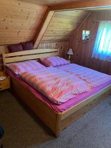 a large bed in a room with a wooden ceiling at Chalupa v Cíšařským in Golčŭv Jeníkov