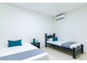 リオアチャにあるHotel Caribe Confortの白い壁の客室で、ベッド2台、青い枕が備わります。