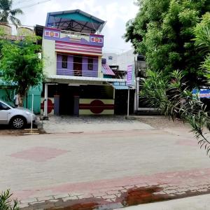 a colorful building on a street with a parking lot at Mahalinga Residency in Tiruvidaimarudūr