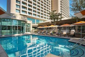 a swimming pool with chairs and umbrellas in a hotel at Warner Center Marriott Woodland Hills in Woodland Hills