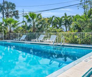 a swimming pool with chairs and palm trees at Sea Dell Motel - Marathon in Marathon