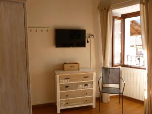 - une chambre avec une commode, une télévision et une chaise dans l'établissement B&B Antica Corte, à Omegna