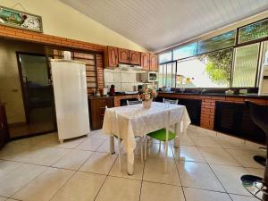 a kitchen with a white table and a refrigerator at Casa ampla com 02 suítes e 01 quarto próx das Cataratas e Aeroporto in Foz do Iguaçu