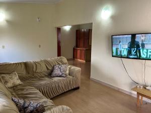 a living room with a couch and a flat screen tv at Casa ampla com 02 suítes e 01 quarto próx das Cataratas e Aeroporto in Foz do Iguaçu
