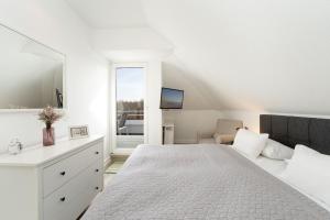 a white bedroom with a large bed and a window at Golfresidenz Ostseebude in Grömitz