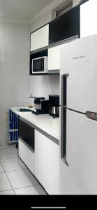 a white kitchen with a refrigerator and a microwave at apartamento sao vicente vista mar pe na areia in São Vicente