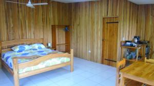 une chambre avec un lit et un mur en bois dans l'établissement Corcovado Tropical Garden Lodge, à Drake