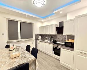 une cuisine avec des armoires blanches et une table avec des chaises dans l'établissement City Stay Apartment - renoviert & klimatisiert, à Sarrebruck