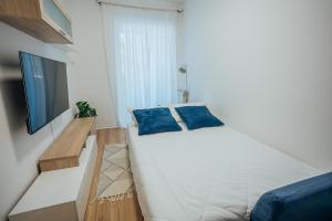1 cama blanca con almohadas azules en una habitación en Dimora Vittoria Apartment, en Montesilvano