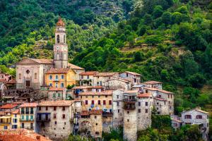 a town with a clock tower on a mountain at l'oiseau bleu in Lucéram