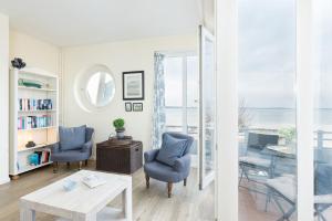 ein Wohnzimmer mit blauen Stühlen, einem Tisch und einem Fenster in der Unterkunft Haus Windjammer Strandliebe in Laboe