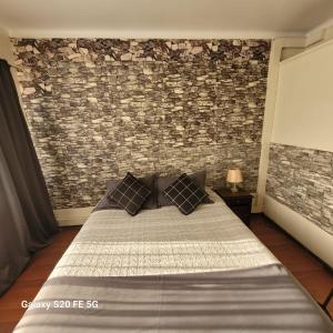 a bedroom with a bed and a brick wall at Hostal Donde Gabriel in Chillán +1 photo
