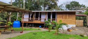 a wooden house with a porch and a yard at Pinocchio Cosy house in Puerto Viejo