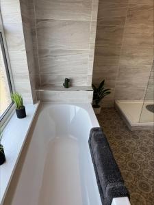 a white bath tub in a bathroom with plants at Valletta House Holiday Apartments in Skegness