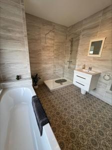 a bathroom with a tub and a shower and a sink at Valletta House Holiday Apartments in Skegness +37 photos