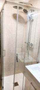 a shower with a glass door next to a sink at Casa Foz do Rio in Caminha