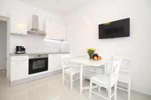 a white kitchen with a white table and chairs at Apartment LU in Split