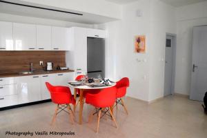 a kitchen with a table and red chairs at Comfort Holidays in Messini