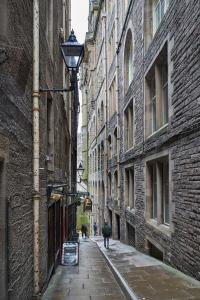 an alley with buildings and a person walking a dog at 3 Bedroom Apartment - Historic Old Town in Edinburgh
