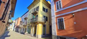 a yellow building with a balcony on a street at Hostpitaly - Il rifugio urbano in Chivasso
