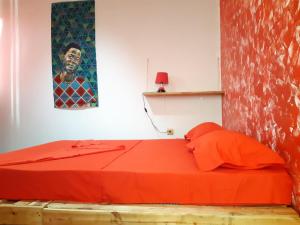 a bedroom with a red bed with a painting on the wall at Kasa Sirena in Tarrafal